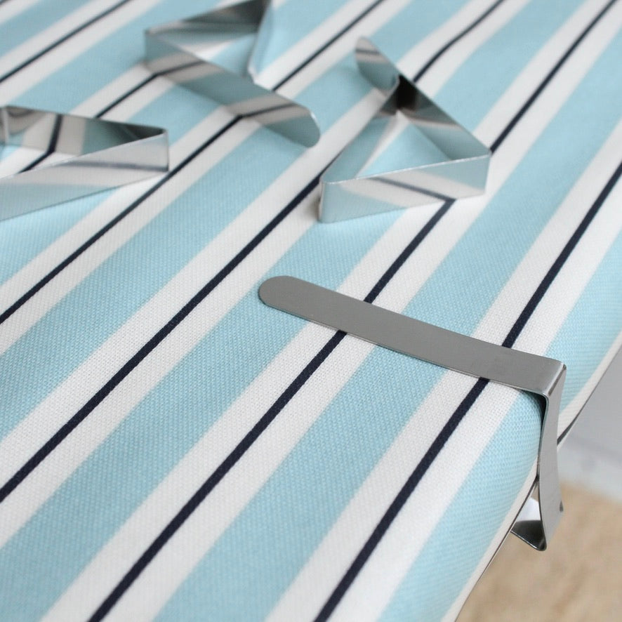 Metallic tablecloth clips on a blue and white striped oilcloth