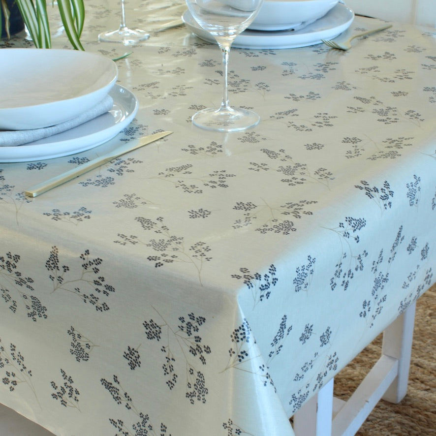 Table setting with floral-patterned tablecloth, plates, and wine glasses.