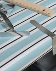 Metallic tablecloth clips on a striped oilcloth background with a ruler for scale.