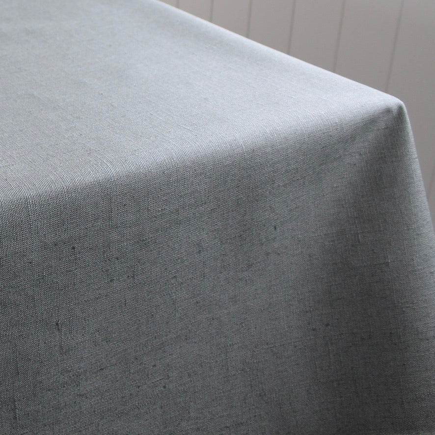 Gray green tablecloth draped over a table with a neutral background