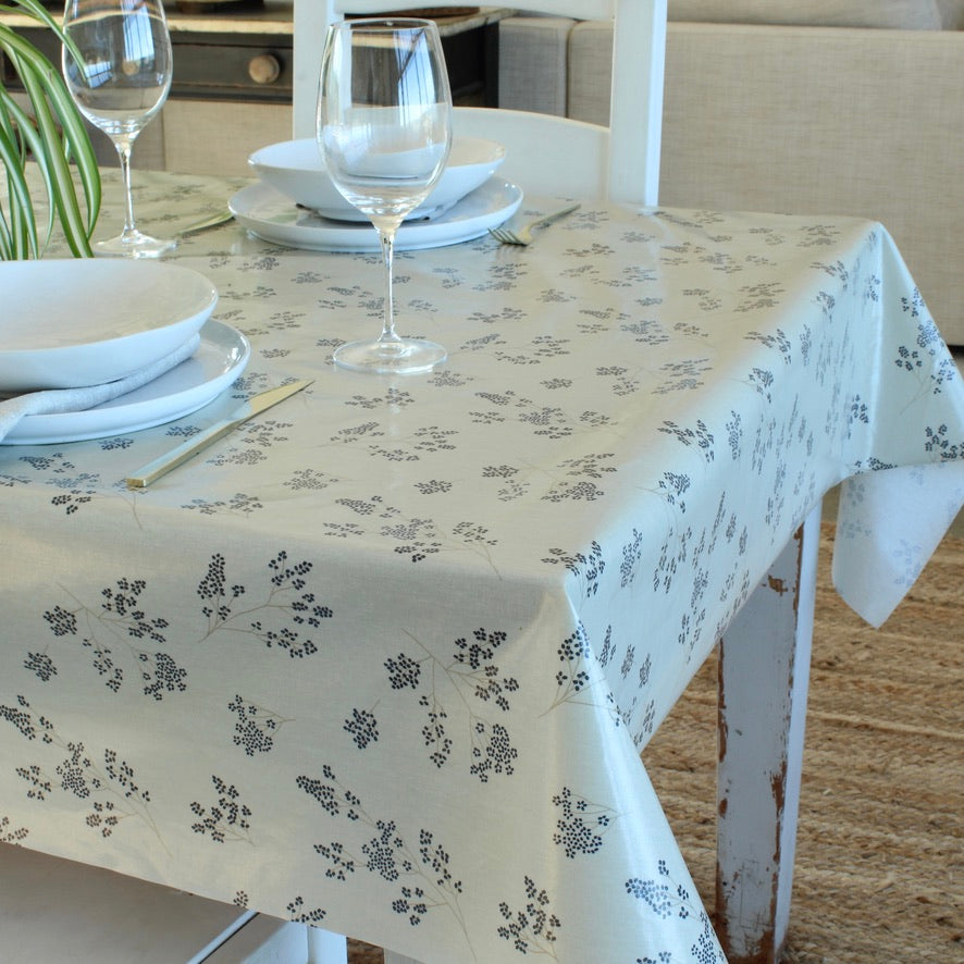Dining table set with floral-patterned tablecloth, plates, and glasses.