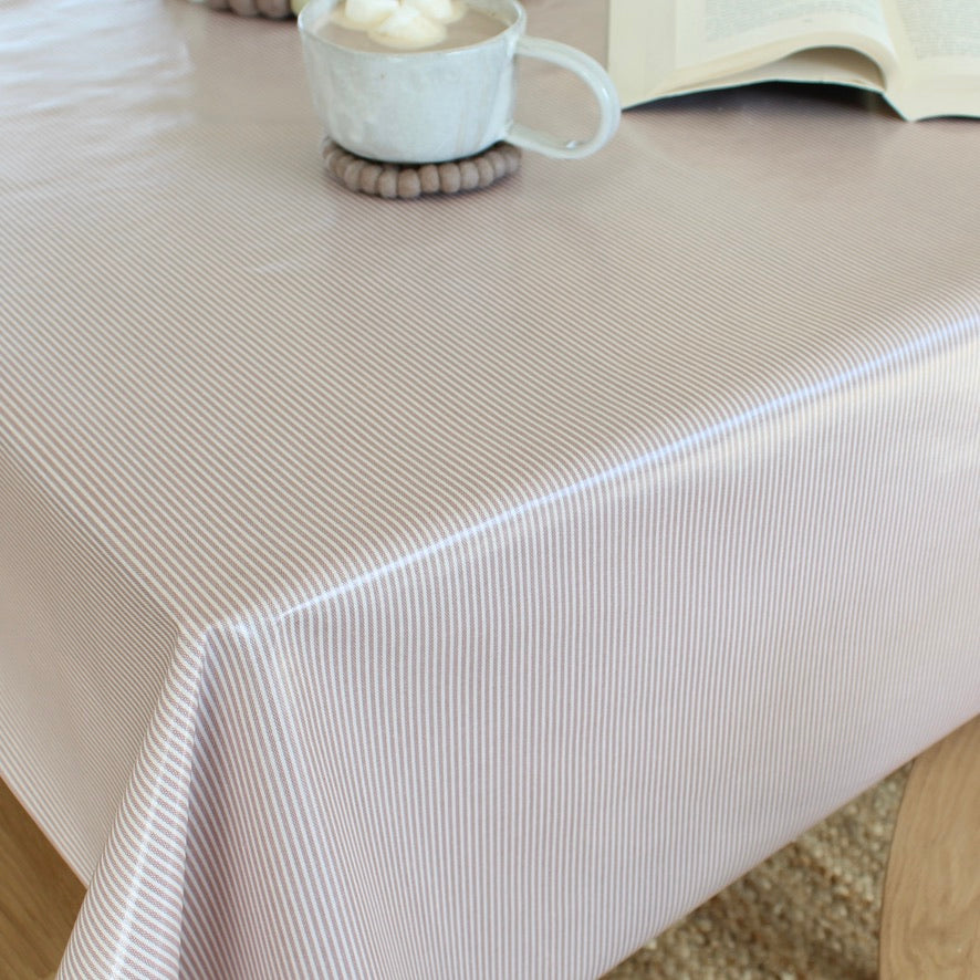 Pink striped tablecloth on a table with a cup and coaster in the background