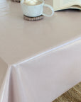 Pink striped tablecloth on a table with a cup and coaster in the background