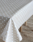 A light beige tablecloth with a white star pattern draped over a table with wooden legs on a woven rug.