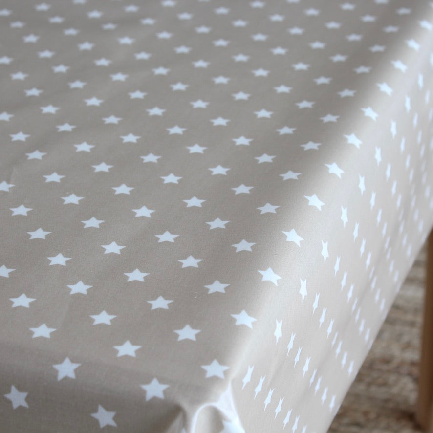 A close-up of a tablecloth with a repeating pattern of small white stars on a warm beige background.