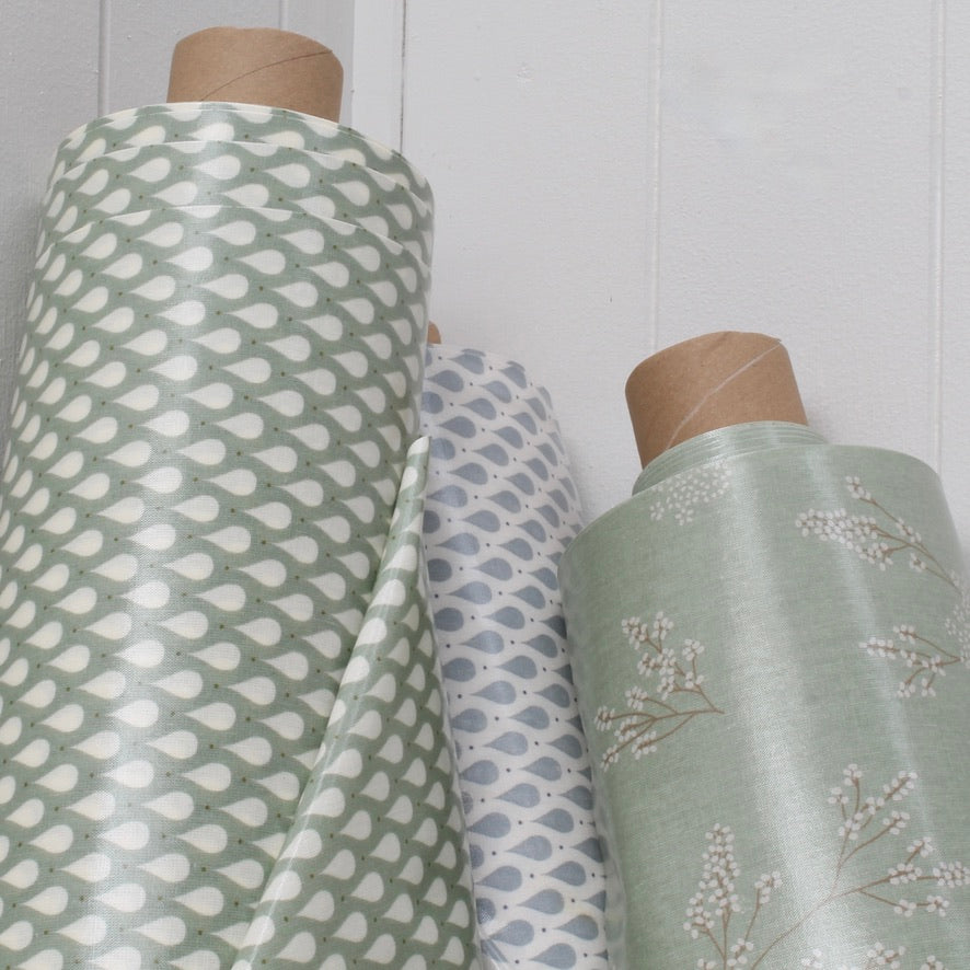 Three rolls of oilcloth with different patterns against a white wall.