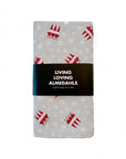 A folded oilcloth featuring a repeating pattern of red christmas gnomes and white snowflakes, wrapped in a black paper band with the text 'LIVING LOVING ALMEDAHLS'.