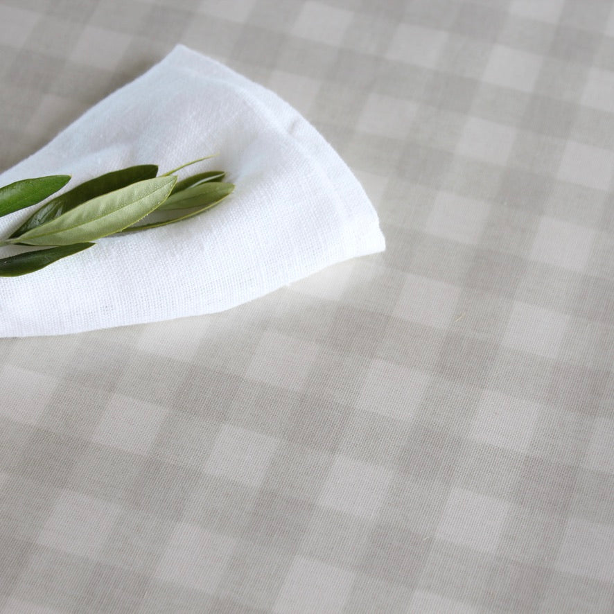 White napkin with green leaves on a beige checkered oilcloth
