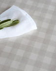 White napkin with green leaves on a beige checkered oilcloth