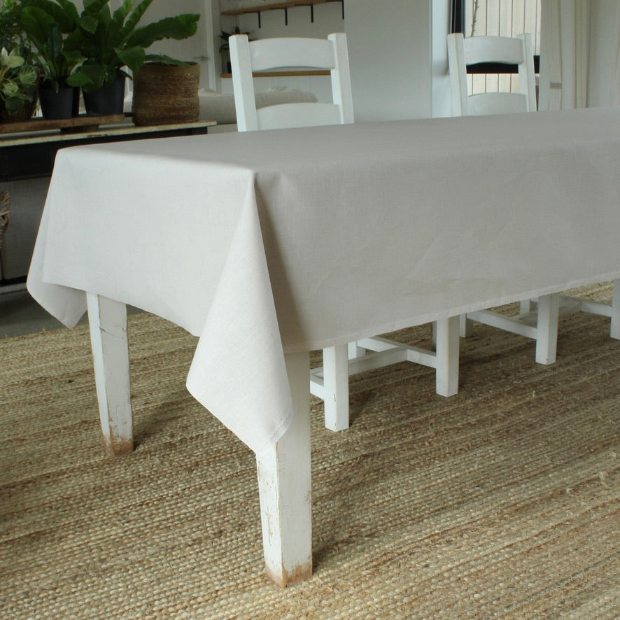 Grey tablecloth on a wooden dining table with chairs in a room.