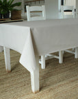 Grey tablecloth on a wooden dining table with chairs in a room.