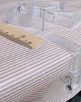 Clear plastic tablecloth clips on a striped oilcloth surface with a wooden ruler for scale.