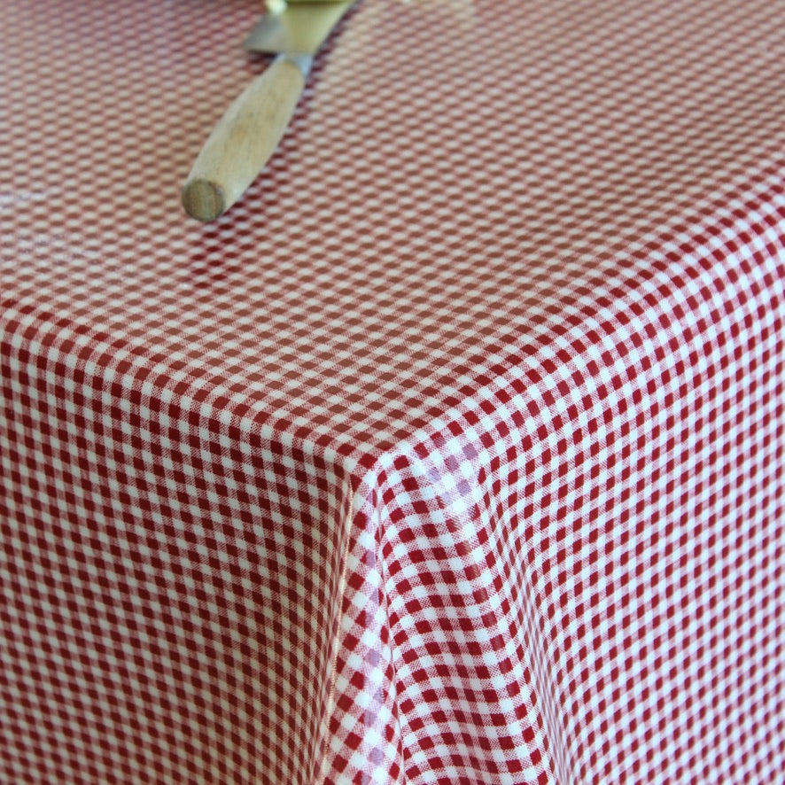 A close-up of a red and white gingham checkered tablecloth draped over a table, with a wooden-handled utensil resting on the surface.