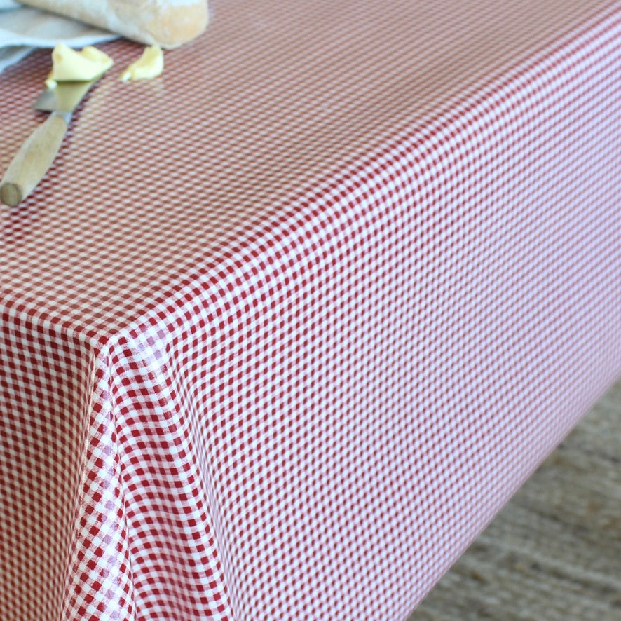 A red and white gingham checkered tablecloth draped over a table, with a knife and butter visible in the top-left corner.