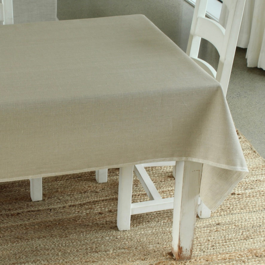 Beige tablecloth on a white table with chairs in a room setting