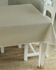 Beige tablecloth on a white table with chairs in a room setting