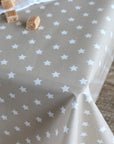 A close-up of a table covered with a beige tablecloth printed with a white star pattern, with a few small wrapped candies placed on the surface.