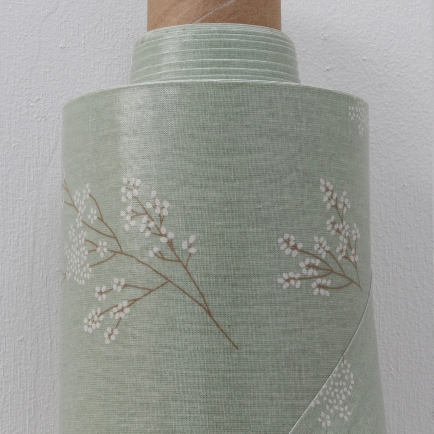 Green oilcloth roll with floral pattern on a white background