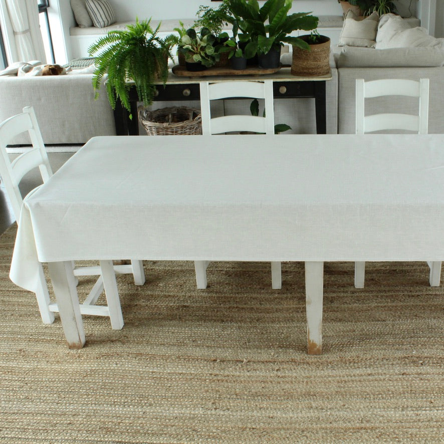 White dining table and chairs in a room with plants and furniture.