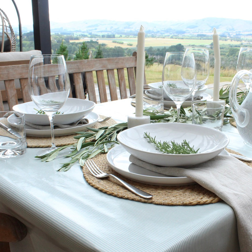 Elegant table setting with white plates, glasses, and napkins on a table with a scenic view.