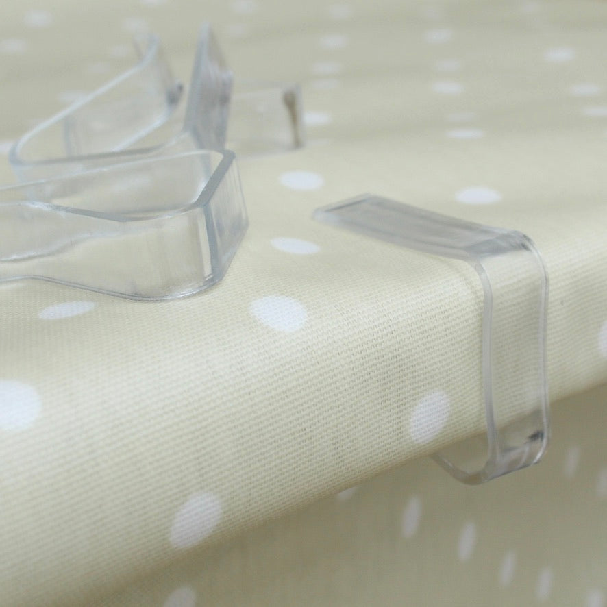 Clear plastic tablecloth clips on a polka dot fabric surface