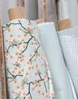 Rolls of oilcloth with floral and checkered patterns on a wooden stand.