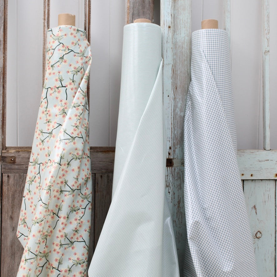 Three oilcloth rolls with different patterns against a wooden background