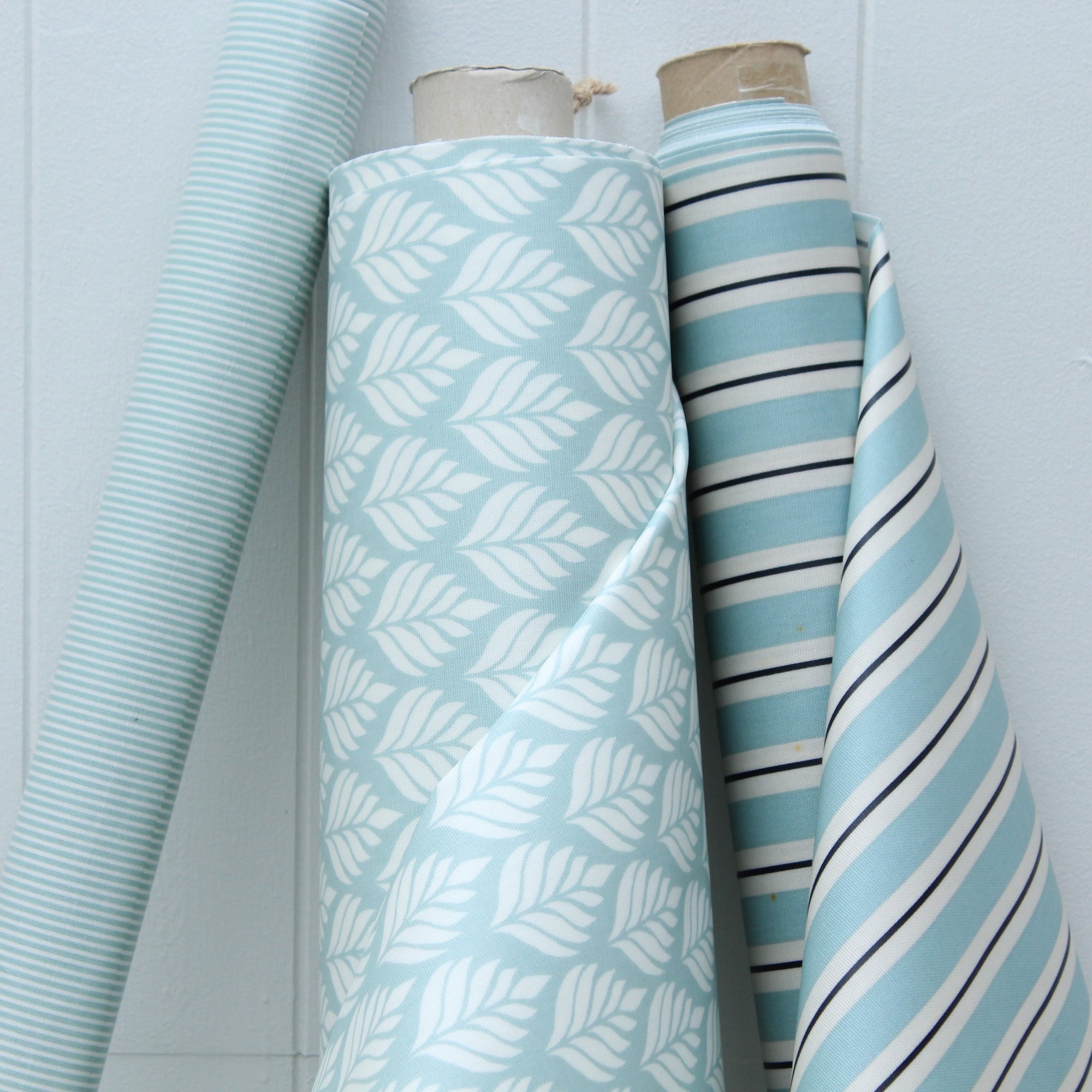 Three rolls of oilcloth with different patterns on a light blue background