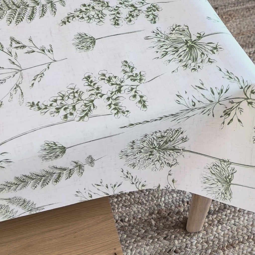 White oilcloth tablecloth with green fern pattern on a wooden table