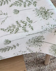 White oilcloth tablecloth with green fern pattern on a wooden table
