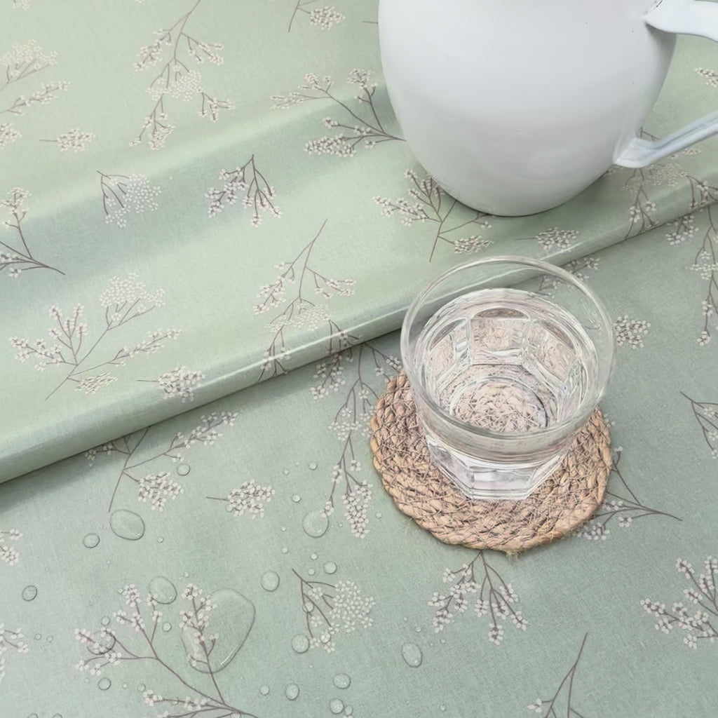 green and white floral oilcloth with a glass of water and a white enamel jug