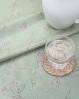 green and white floral oilcloth with a glass of water and a white enamel jug