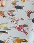 someone breaking an egg onto a chicken design oilcloth and wiping it up