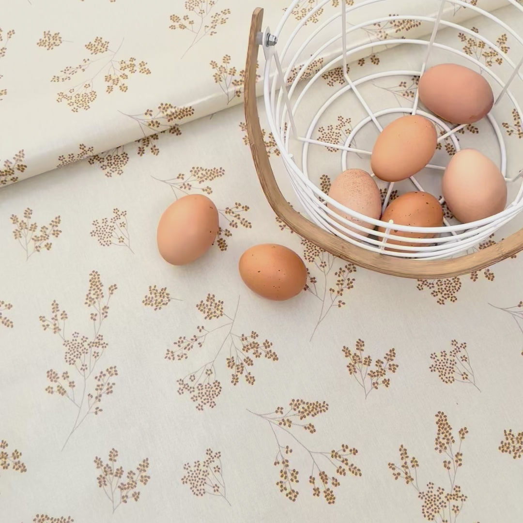white oilcloth with yellow flower design and some eggs in a basket