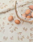 white oilcloth with yellow flower design and some eggs in a basket