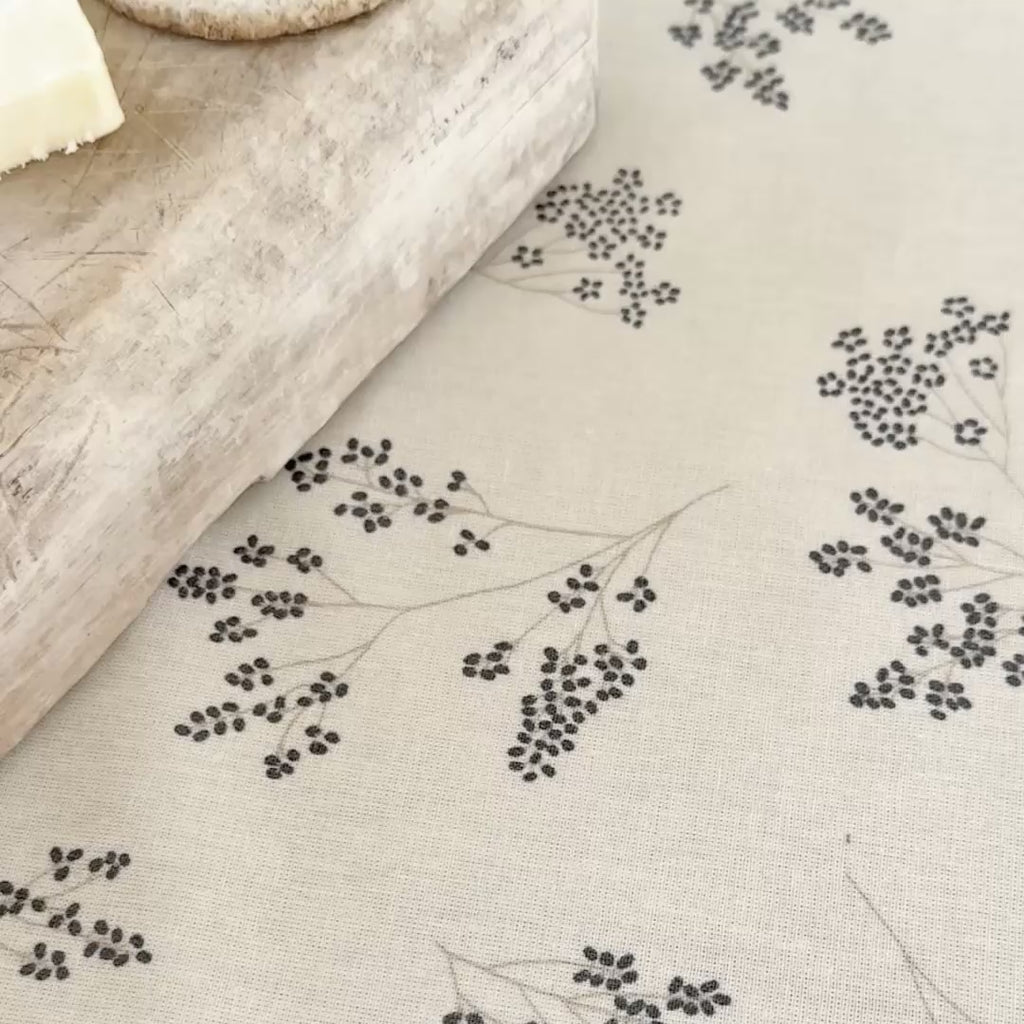 chutney being spread onto a white tablecloth with blue flower pattern and wiped up.