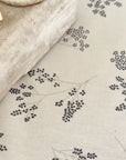chutney being spread onto a white tablecloth with blue flower pattern and wiped up.