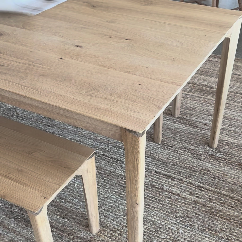 Wooden table being covered with a striped blue white and beige tablecloth