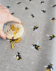 Bee design on a beige oilcloth with a crumpet and honey spilt onto the tablecloth.  The honey is then wiped off easily.