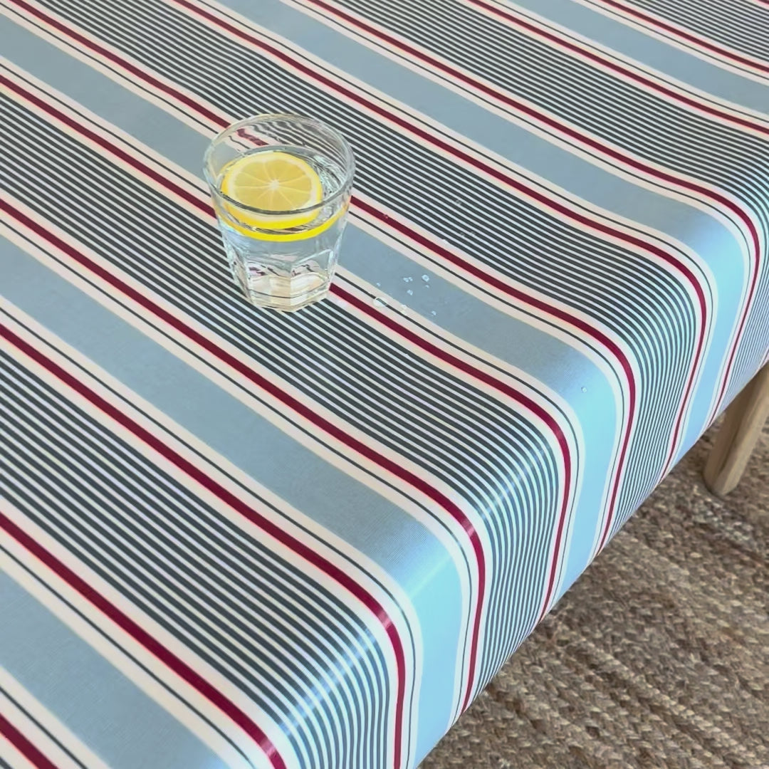 glass of water with water droplets sitting on top of a red white and blue striped oilcloth