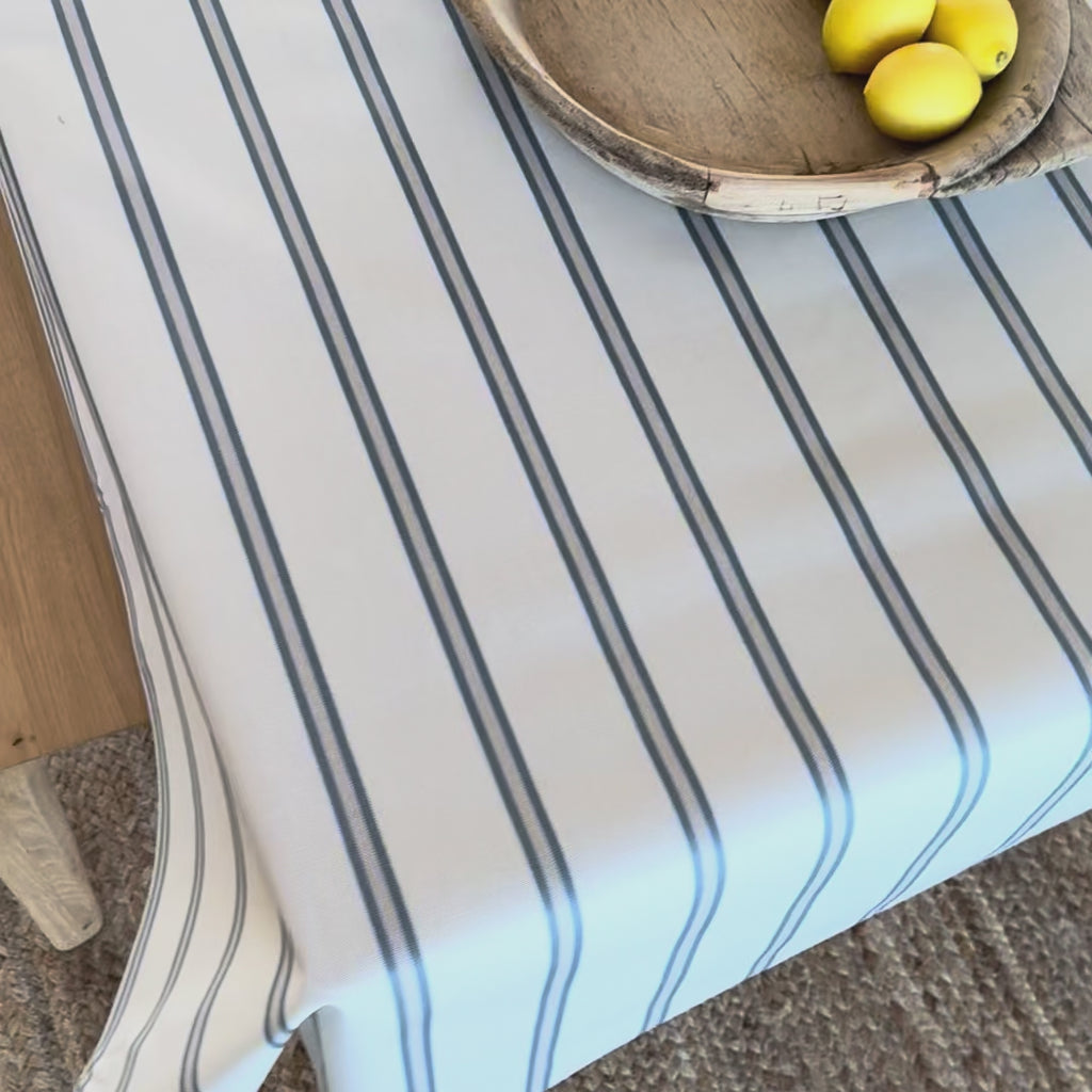 Blue and white striped oilcloth on a wooden table with a wooden bowl and lemons