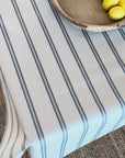 Blue and white striped oilcloth on a wooden table with a wooden bowl and lemons