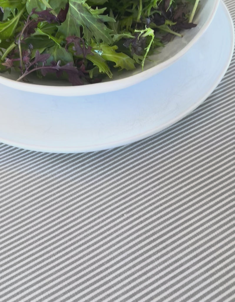 video of olive oil being spilled onto a stripe grey tablecloth then wiped away