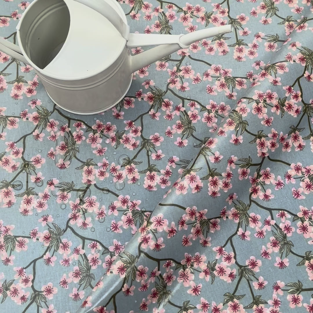 Floral oilcloth with pink flowers on a blue background and a watering can
