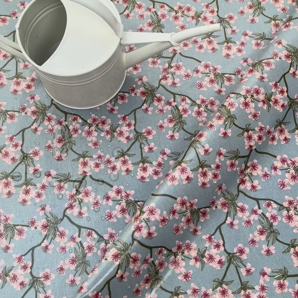 Floral oilcloth with pink flowers on a blue background and a watering can
