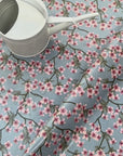 Floral oilcloth with pink flowers on a blue background and a watering can