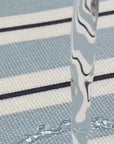 water being poured ono a wipe clean blue and white striped tablecloth