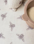 Baby food being dropped on a bee patterned beige tablecloth then wiped clean easily