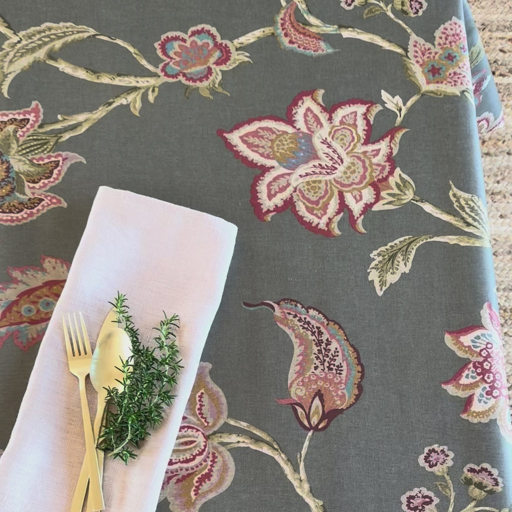 dark tablecloth with floral pattern and napkin with gold cutlery and rosemary sprig