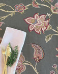 dark tablecloth with floral pattern and napkin with gold cutlery and rosemary sprig